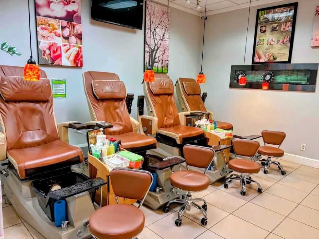 Row of leather pedicure spa chairs under amber pendant lamps